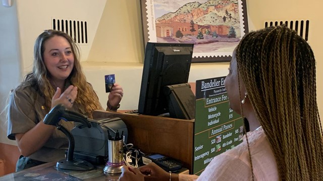 A female park ranger talks to a female visitor inside a building. 